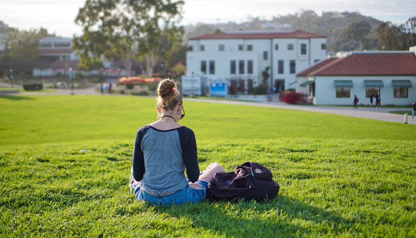 SBCC student sitting on the west campus lawn studying.